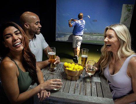 Friends drinking at indoor golf venue