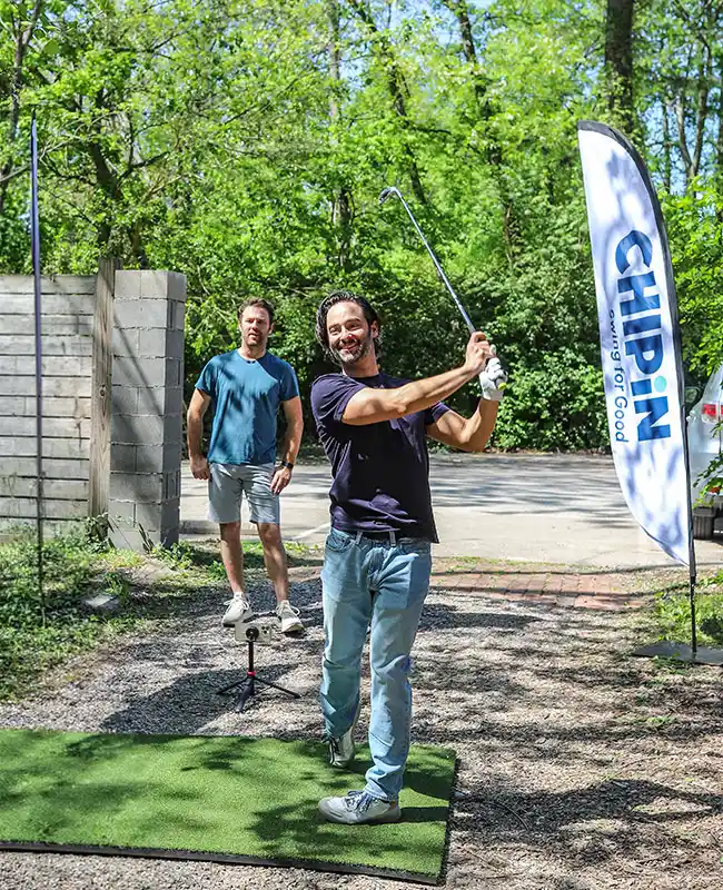 Two friends smiling in front of a golf simulator screen